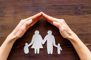 Live insurance concept. Family silhouette under palm on dark wooden background top-down
