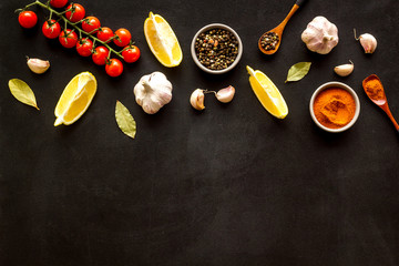 Cooking background with spices and vegetables. pepper, garlic, cherry tomatoes on black desk top-down frame copy space