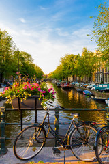Bike parked at a bridge over a canal decorated with flowers in Amsterdam, Netherlands © reubergd