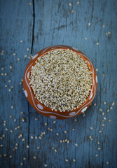 Sesame seeds in clay pot on wooden background