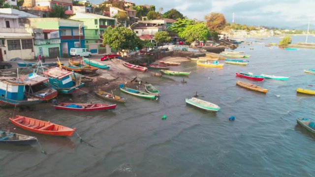 Aerial dynamic shot of a Fishing Village in Rio de Janeiro, Brazil. Tropical beach landscape with wooden boats on the polluted water
