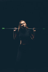 Defiant athletic girl on a dark background. Dramatic portrait. Toned.