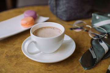 A cup of coffee with milk and berry macaroons.