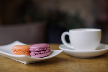 Berry macaroons and mug of hot cocoa on wooden table.
