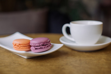 Berry macaroons and mug of hot cocoa on wooden table.