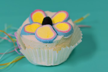 A small, colorful cupcace lies against a colorful background as a close-up for an invitation