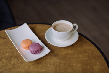 A cup of coffee with milk and berry macaroons.