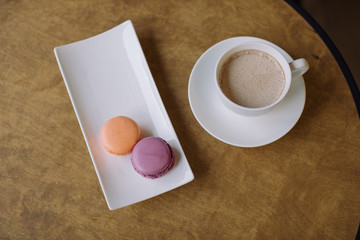 Berry macaroons and mug of hot cocoa on wooden table.