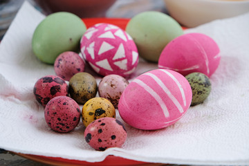 Obraz na płótnie Canvas Homemade colorful easter eggs and bowls with egg dye on the table, lifestyle