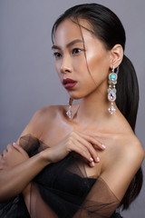 Beauty portrait of a beautiful Asian girl with large southeast earrings Isolated on a gray background.