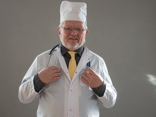 Portrait of elderly doctor with gray hair and glasses in white coat and medical cap with stethoscope looks through medical history. solid professor evoking positive emotions and patient confidence