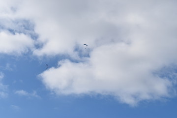 Paraglider in the wide blue sky with a white cloud in background