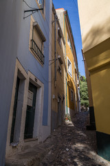 Fototapeta premium Empty and narrow cobblestoned alley in the Alfama district in Lisbon, Portugal, on a sunny day.