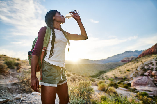 african american woman taking a break to drink from water bottle while hiking at red rock canyon nevada