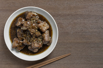 top view of stir fried pork rib with black pepper sauce in a ceramic dish on wooden table. homemade style food concept.