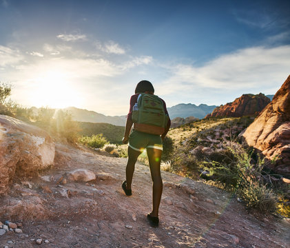athletic african american woman hiking through red rock canyon in nevada at sunset