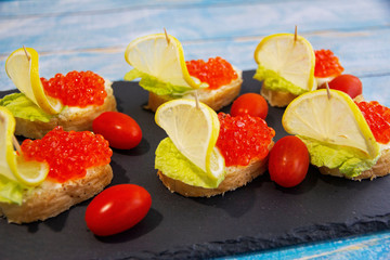 Red caviar bruschetta with butter, lettuce and cherry tomatoes