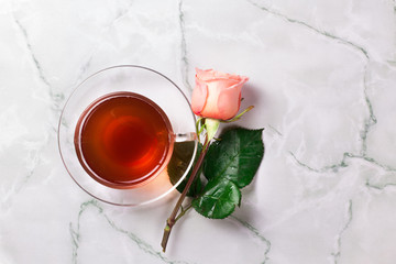 Cup of morning tea and roses on a marble background..Rose petals.