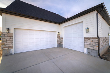 Two garage doors sharing a paved forecourt
