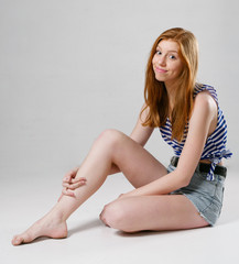 Naklejka premium young girl with long red hair on a gray background