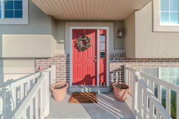 Walkway to a colorful red front door with wreath