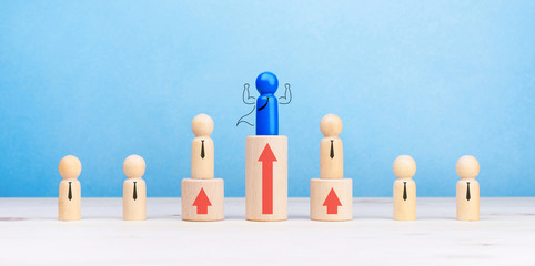 Business competition and Leadership concept with wooden figures of people symbol and arrow up on the table, blue background, copy space