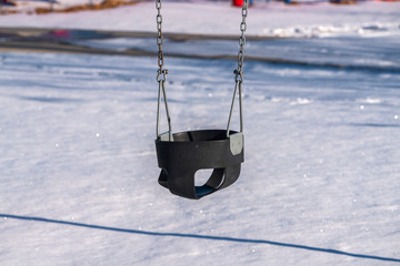 Kids swing in a winter playground day light
