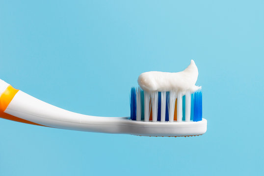 Toothbrush with white toothpaste close-up on blue background