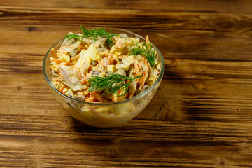Tasty salad with chicken breast, roasted mushrooms, carrots, grated cheese, eggs and mayonnaise on wooden table