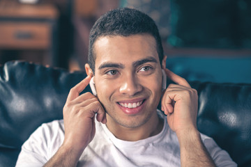 Handsome smiling guy in white wireless headphones.