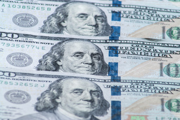 Obraz na płótnie Canvas Background of one hundred dollar bills. Benjamin Franklin on USA money banknote. American dollars banknotes background. US dollars pattern. 100 dollars. Close-up selective focus