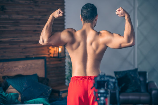 Young Fit Sportive Vlogger In Red Shorts Demonstrating His Strong Shoulders