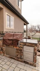 Vertical Covered stone outdoor kitchen on a paved patio