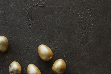  Golden easter quail eggs on a dark gray rough background copy space.