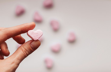  Pink marshmallow in the shape of a heart in a female hand copy space.