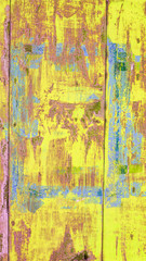 background of brightly painted metal garage wall in yellow, blue and pink colors with scratches and rust