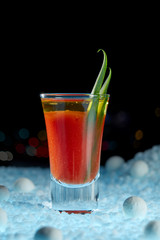 Bloody Mary cocktail close-up, decorated with greenery, in a surreal landscape on a black background with a fabulous bokeh. Copy space. Vertical.