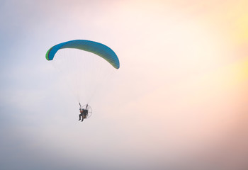 A man is flying with a powered parachute over the beach in Thailand.