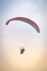 A man is flying with a powered parachute over the beach in Thailand.