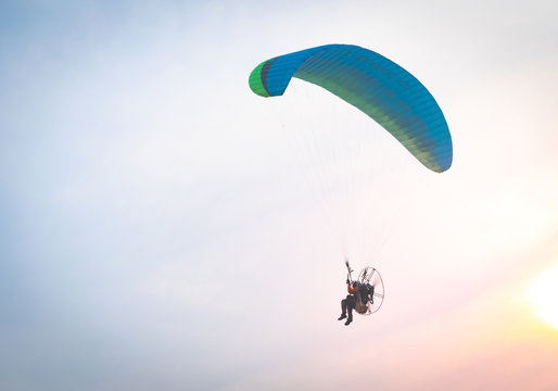 A man is flying with a powered parachute over the beach in Thailand.