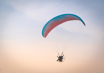 A man is flying with a powered parachute over the beach in Thailand.