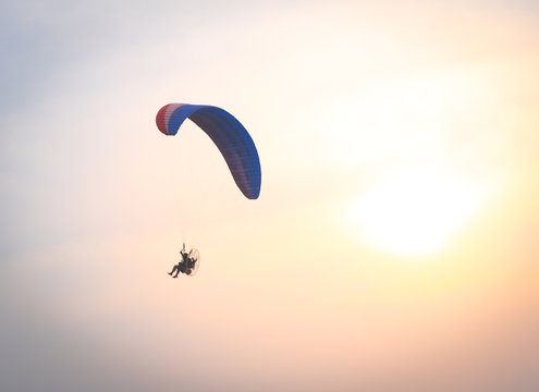 A man is flying with a powered parachute over the beach in Thailand.
