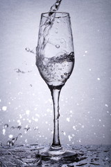 liquid stream going into glass goblet, water splashes, light from back
