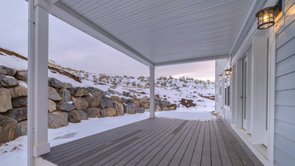 Panorama frame Covered wooden exterior patio facing a stone wall