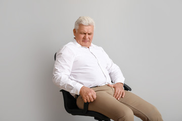 Mature man with urologic disease on light background