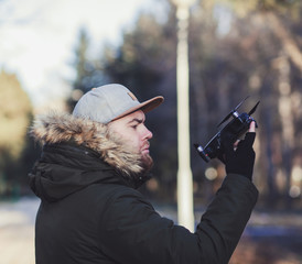 Man in coat holding drone in park