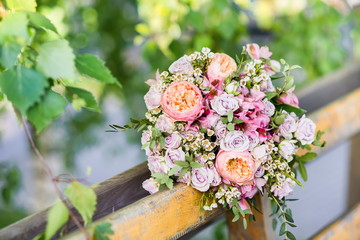 Beautiful wedding bouquet of pink and beige roses on a brown wooden bench
