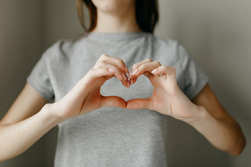 Gray t-shirt on the girl. Paper white heart, medicine. A heart from a woman's crossed arms.