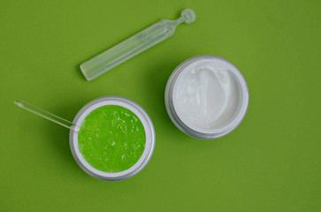 Face cream, serum, glass stick, on a green background, close-up