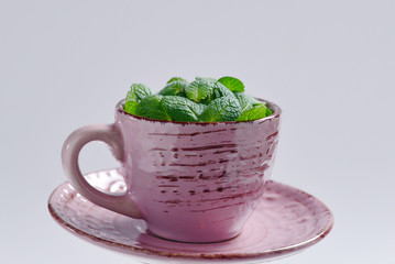 Mint leaves in a cup isolated on white background.